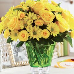 Emilee's Flowers and Events - A cheerful arrangement of bright yellow roses and daisies displayed in a vibrant green glass vase, creating a sunny and uplif...