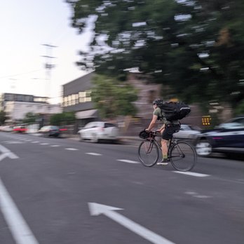 CCC PDX - a man riding a bike with a backpack on his back - Food Delivery Services Near Me - Portland, Oregon
