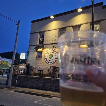 Sawstone Brewing - a person holding a beer in front of a building - Breweries Near Me - Morehead, Kentucky
