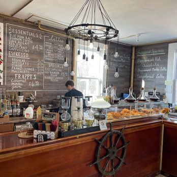 Java Smugglers - A coffee shop interior featuring a wooden counter with a ship's wheel decoration, black chalkboard menus, and a chandelier with hanging light bulbs. - Juice Bars & Smoothies Near Me - Boonton, New Jersey