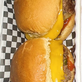 The Beer Keep - Two cheeseburgers with beef patties, melted yellow cheese, and toppings such as vegetables are served in soft buns. They are placed on black and white checkered paper, likely in a food service setting. - Beer Bar Near Me - Buffalo, New York