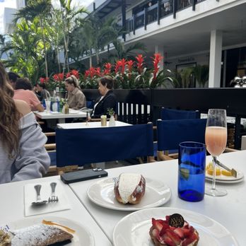 Avenue 31 Cafe - a woman sitting at a table with desserts - Pasta Shops Near Me - Bal Harbour, Florida