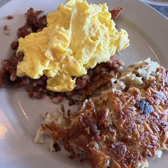 Maxfields Pancake House - Corned Beef Hash and Eggs (3) - A breakfast plate features scrambled eggs with corned beef hash and a portion of hash browns, served on a white dish. - Breakfast & Brunch Near Me - Schaumburg, Illinois