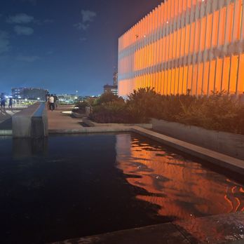 POST Houston - An adjacent building lit from within by a single row of orange lights, taped down to the wooden floor on all sides, on every level. - Music Venues Near Me - Houston, Texas POST Houston - An adjacent building lit from within by a single row of orange lights, taped down to the wooden floor on all sides, on every level. - Music Venues Near Me - Houston, Texas