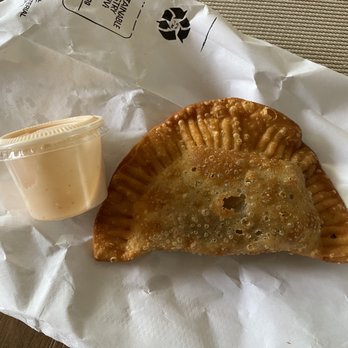Pa'l Monte - Beef pasteLito with sauce - A fried empanada with a crispy, golden-brown exterior is placed on a paper-lined tray, accompanied by a small container of dipping sauce. - Food Trucks Near Me - Smithfield, Rhode Island
