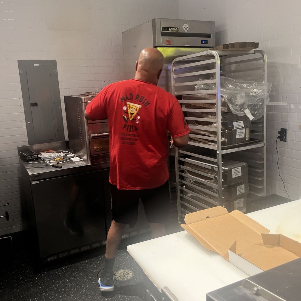 Mad Rush Pizza - Laron pulling out a hot pizza. - Pizza Near Me - Mequon, Wisconsin