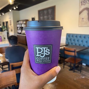 PJ's Coffee - a hand holding a purple coffee cup - Cafes Near Me - Ruston, Louisiana