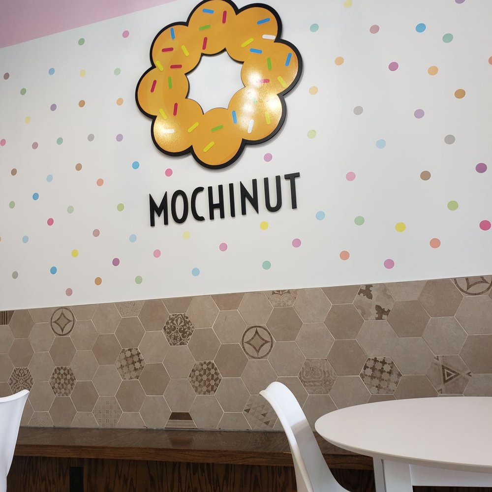 Mochinut - This is their logo posted on the wall. The dining area is set up from large groups to come in and enjoy their wonderful offerings. - Donuts Near Me - Plano, Texas Mochinut - This is their logo posted on the wall. The dining area is set up from large groups to come in and enjoy their wonderful offerings. - Donuts Near Me - Plano, Texas