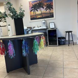 Aten Dental Group - Table and fridge in the lobby. Fridge is stocked with juices, water, and a coffee station. There's also tooth brushes.