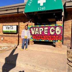 Vape Colorado - The owner standing next to the handmade banner from Mike McPuff on opening day.