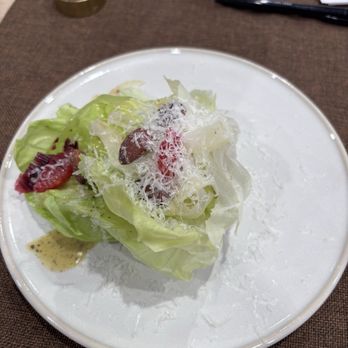The Recipe - A salad with lettuce, strawberries, and cheese shavings is served on a white plate, with a small dressing on the side. - Venues & Event Spaces Near Me - Ames, Iowa
