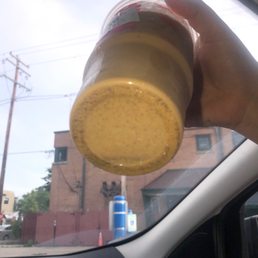  a hand holding a cup of mustard