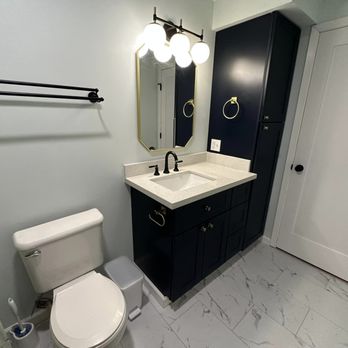 DW Home Improvement - a bathroom with a toilet, sink, and mirror - General Contractors Near Me DW Home Improvement - a bathroom with a toilet, sink, and mirror - General Contractors Near Me