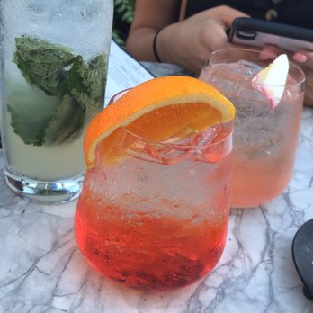 Ouzo Bay - Happy hour drinks-- left- mojito, middle- aperol spritz, right- rose cocktail - Greek Near Me - Baltimore, Maryland Ouzo Bay - Happy hour drinks-- left- mojito, middle- aperol spritz, right- rose cocktail - Greek Near Me - Baltimore, Maryland