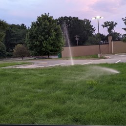 a sprinkler spraying water in a parking lot a sprinkler spraying water in a parking lot