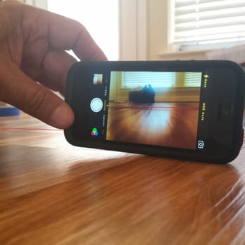 Empire Today - the phone in the photo is sitting flat- lying on one plank but is lifted off of the second plank due to the warping - Flooring Near Me