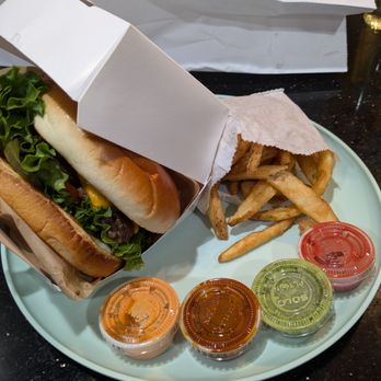 Rg Kitchen - The lamb cheeseburger unboxed with the side of fries and 4 sauces - Burgers Near Me - Fairfield, California