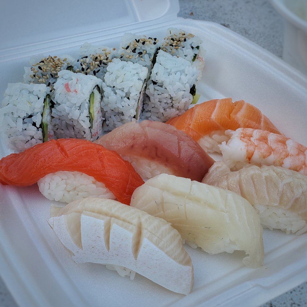 a variety of sushi in a styrofoam container