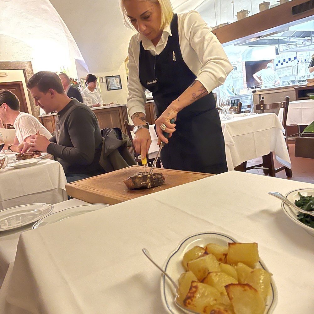 Buca Lapi - Cutting our steak table side. Tasty potatoes foreground. - Tuscan Near Me - Florence, FI Buca Lapi - Cutting our steak table side. Tasty potatoes foreground. - Tuscan Near Me - Florence, FI