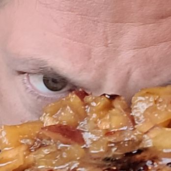 Shenanigans - The image shows a person with light skin and dark hair, with only one eye, part of the forehead, and some hair visible. In front of them is a plate of food containing broccoli and a dish with sauce and chunks of meat or vegetables. The person appears to be looking over the food, with the focus on their eye and the plate. - Music Venues Near Me - Lake Harmony, Pennsylvania