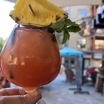 Lakanuki - a person holding a glass of drink with a pineapple garnish on top - Tiki Bars Near Me - Mammoth Lakes, California Lakanuki - a person holding a glass of drink with a pineapple garnish on top - Tiki Bars Near Me - Mammoth Lakes, California