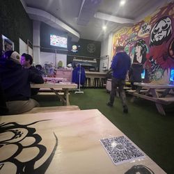 Picnic tables with video games at each table, turf, TV, small bar, table service