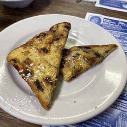 Banana French Toast - Two slices of raisin bread French toast dusted with powdered sugar on a white plate, set on a wooden table.