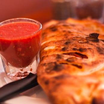 Coalfire Pizza - Shot of marinara alongside a calzone - Pizza Near Me - Chicago, Illinois Coalfire Pizza - Shot of marinara alongside a calzone - Pizza Near Me - Chicago, Illinois