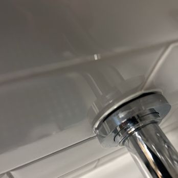 Speedy Gonzalez - A close-up image of a metallic toilet flush handle mounted on a toilet tank. The background shows white tiled walls, indicating a bathroom setting. The handle is shiny and reflective, with the tank surface smooth and clean. - General Contractors Near Me