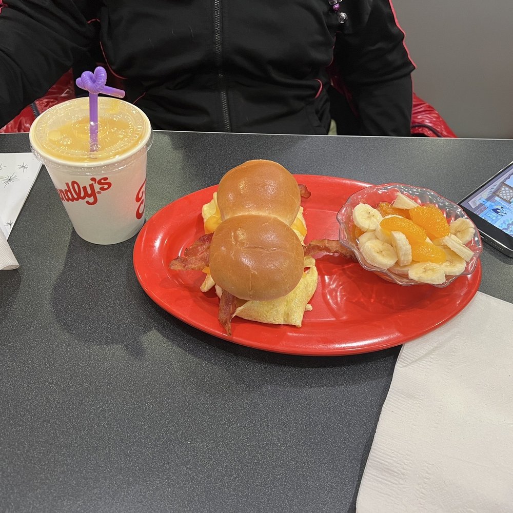 Bacon egg and cheese sliders and bowl of fruit bananas and oranges.