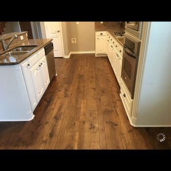 Floor It - a kitchen with white cabinets and wood floors - Flooring Near Me - Rockwall, Texas