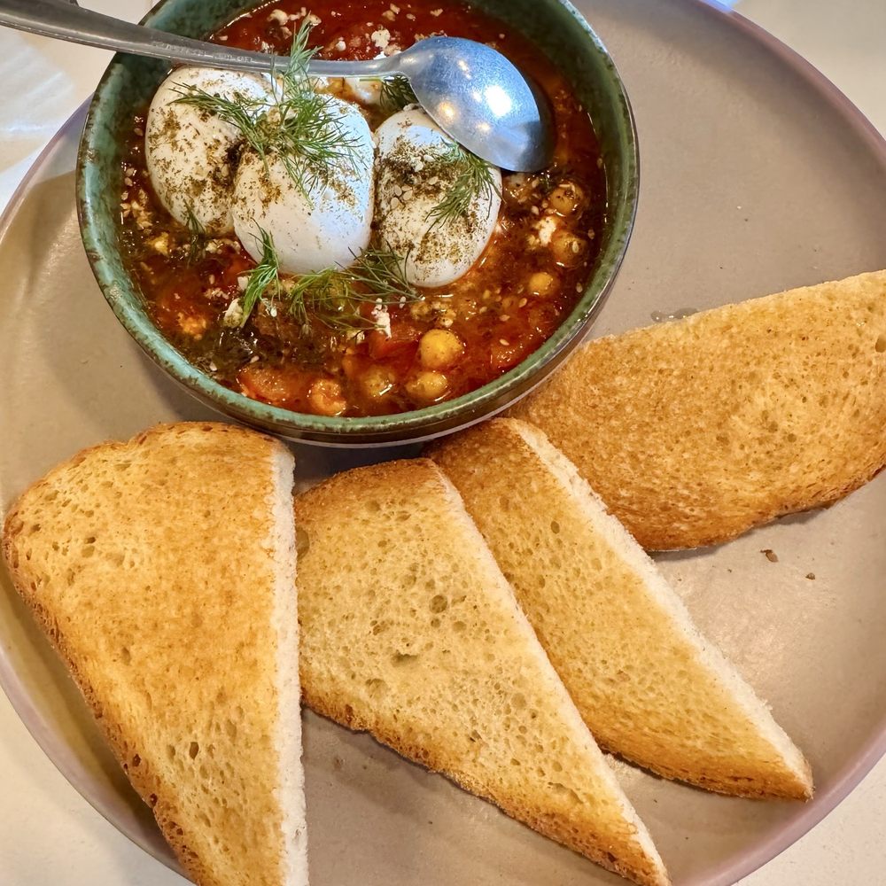 SHAKSHUKA Plum tomatoes, lemon, peppers, jalapeños, Za'atar spice, chickpeas, poached eggs, feta, herbs, rye bread + ordered one extra egg SHAKSHUKA Plum tomatoes, lemon, peppers, jalapeños, Za'atar spice, chickpeas, poached eggs, feta, herbs, rye bread + ordered one extra egg