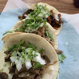 One spicy pork one beef and one regular Pork Taco With onion and cilantro on corn tortillas