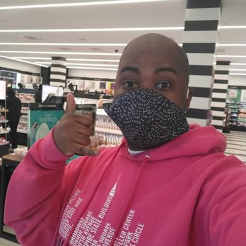 SEPHORA - A person in a pink hoodie and black face mask is taking a selfie inside a retail store, with shelves and displays visible in the background. - Cosmetics & Beauty Supply Near Me - Brooklyn, New York