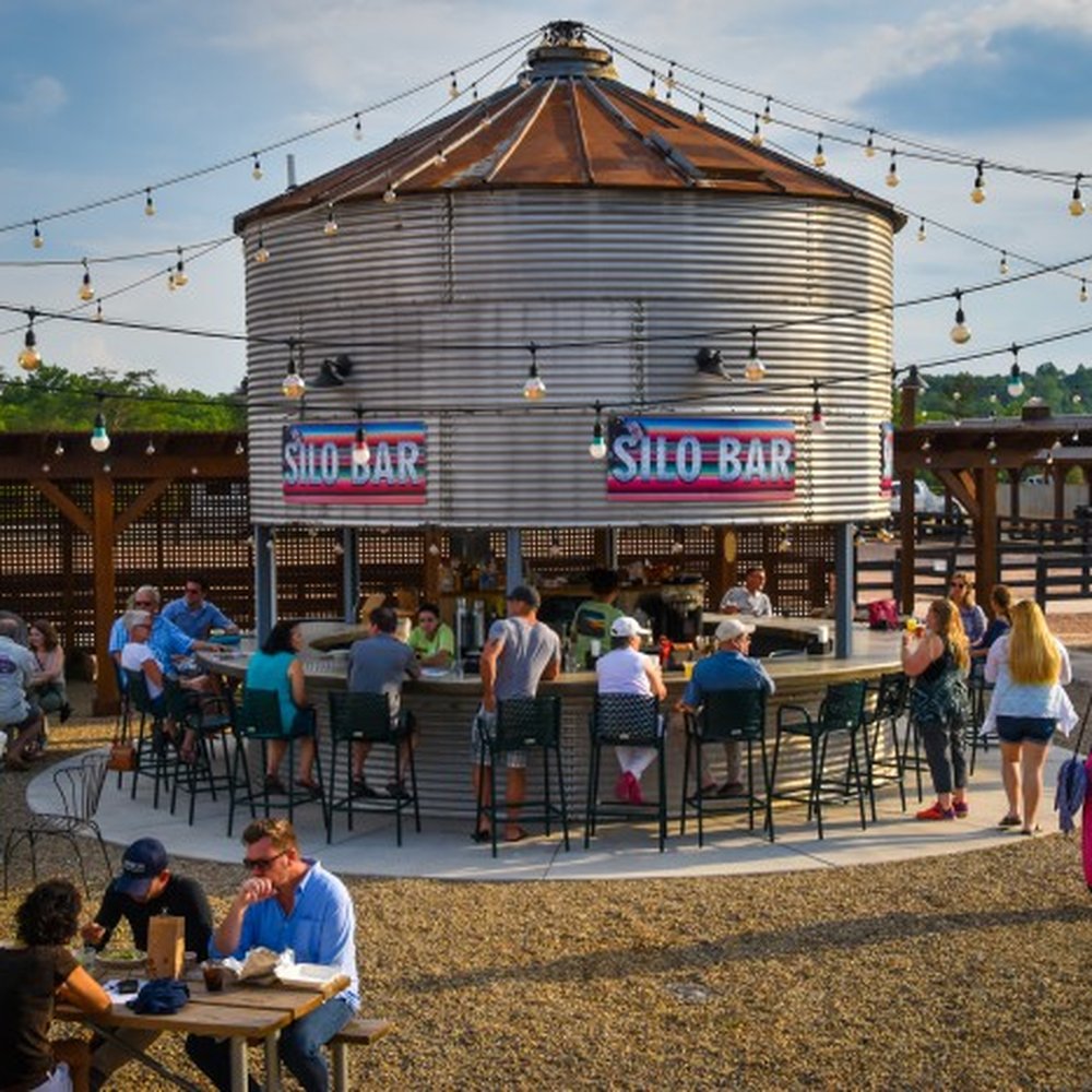 The Silo Bar - a group of people sitting at tables in front of a silo - Bars Near Me - Mill Spring, North Carolina