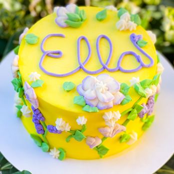 Aria Hungry - a yellow cake decorated with purple and white flowers - Bakeries Near Me