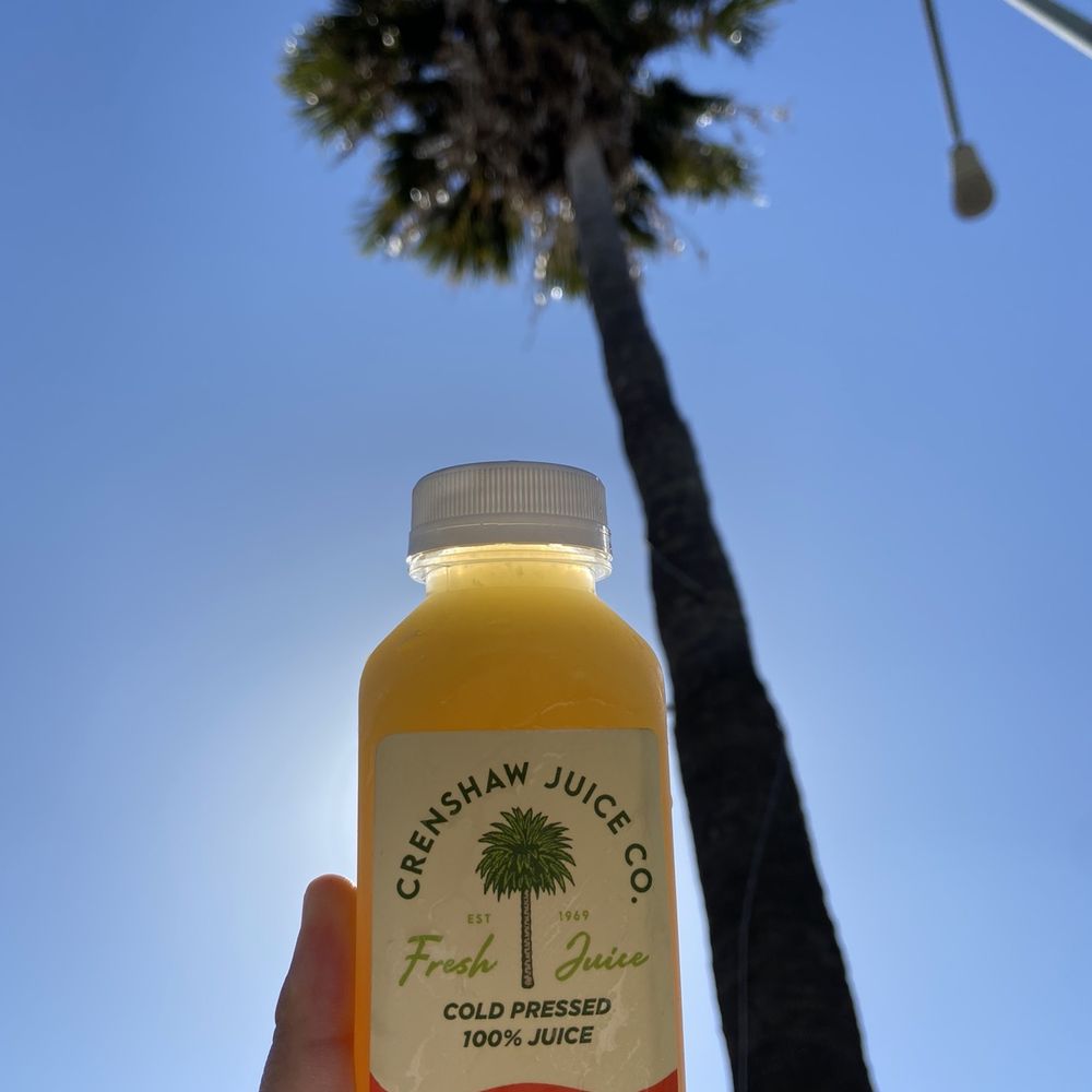 Crenshaw Juice - a person holding a bottle of orange juice - Juice Bars & Smoothies Near Me - Los Angeles, California