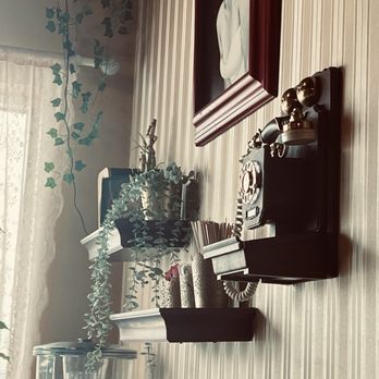 Beyond Cafe - Antique liked dial phone on the wall. - A wall shelf holds a vintage rotary phone, a Marilyn Monroe portrait, and decorative items, with a window and curtains in the background. - Coffee & Tea Near Me - Orleans, Ontario