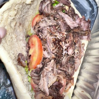 Crown Restaurant - Beef Shawarma - A beef shawarma sandwich features sliced cooked beef, tomato slices, and lettuce inside a pita bread, served in a metal tray. - Mediterranean Near Me - Phoenix, Arizona