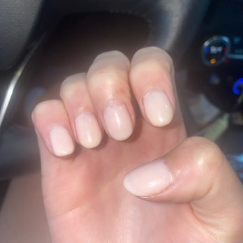 Deview Nail Spa - The image shows a close-up of a person's left hand with well-maintained, light-colored manicured nails. The hand is positioned inside a vehicle, with the dashboard, climate controls, and steering wheel partially visible in the background. The nails are glossy and evenly shaped, indicating recent nail care or manicure. - Nail Salons Near Me - Covington, Louisiana