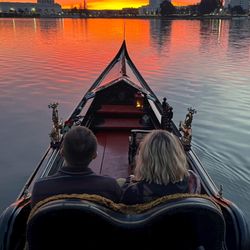 Dolce Vita Gondola - A couple riding in a Venetian gondola on Lake Merritt in Oakland California looks at a beautiful sunset.