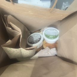 Bagels in a regular paper bag with cream cheese and napkins sitting on top. Bagels in a regular paper bag with cream cheese and napkins sitting on top.