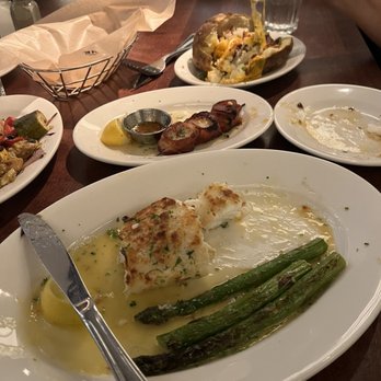 Wildfire - Macadamia Nut Crusted Halibut and Applewood Smoked Bacon - Wrapped Sea - Scallop Skewers in middle w Loaded Baked Potato in the back - Steakhouses Near Me - McLean, Virginia