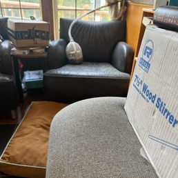 Dog bed near the coffee and dusty chair holding a hose inside a water jug. Dog bed near the coffee and dusty chair holding a hose inside a water jug.