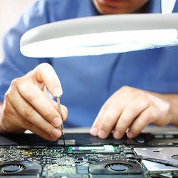 New Start Computer Repair - Removing a part from a laptop motherboard.