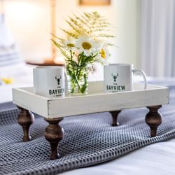 The Bayview Hotel - two Bayview Hotel brand mugs sit on either side of a small floral centerpiece on a wooden bed tray with four ornate legs