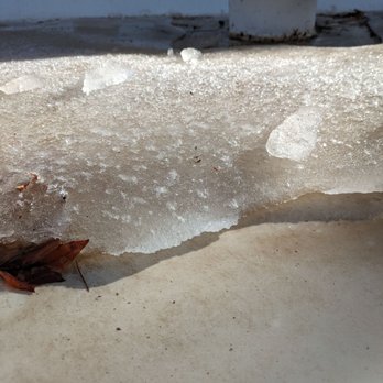 Paramount Roofing - The image shows melting ice on a concrete surface with a fallen leaf nearby, with a white vent or pipe in the background. - Roofing Near Me - Albuquerque, New Mexico