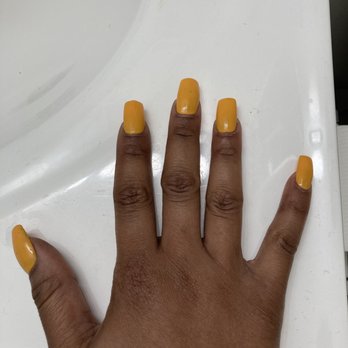 Cosmo Nail Bar - This nail set after we were in conflict was now $65. - A hand with dark skin tone displays yellow painted nails, resting on a white surface, possibly in a salon or personal setting. - Nail Salons Near Me - Washington, DC, District of Columbia