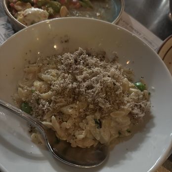 Toro - A bowl of pasta with shredded cheese and herbs, accompanied by a side dish in the background, on a restaurant table. - Tapas Bars Near Me - Boston, Massachusetts