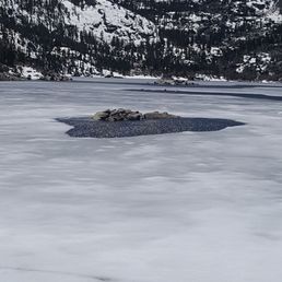1/2 frozen lake. Surrounded by beautiful snow topped mountains.